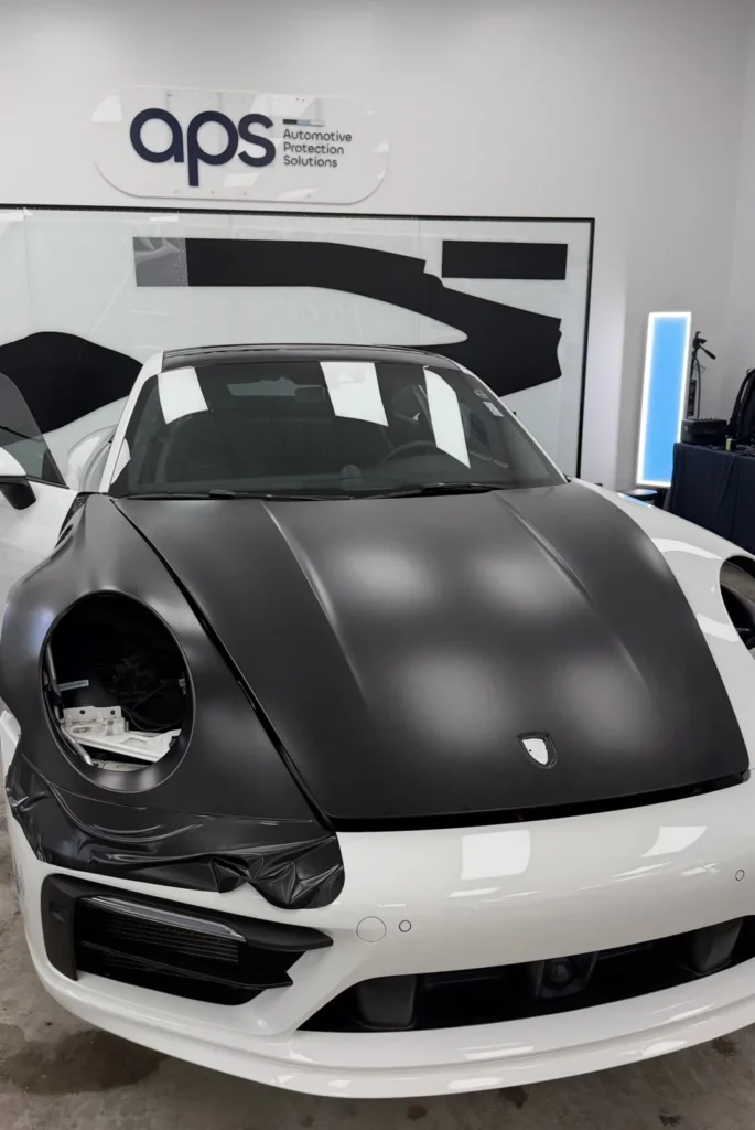Porsche 911 with headlights removed during white to black color PPF wrap