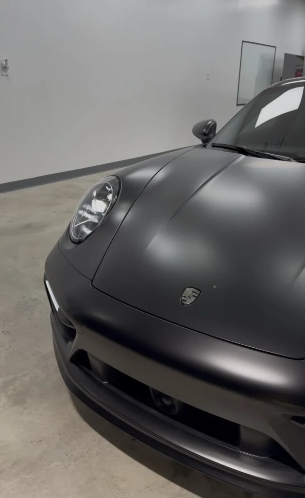 Close-up of XPEL Satin Midnight Black PPF on a Porsche 911 hood and fender