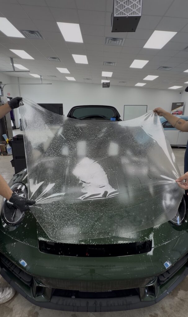 Installers laying XPEL Ultimate Fusion PPF on the hood of a Porsche 911 Targa 4S at APS in Austin, TX