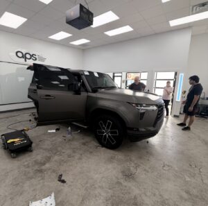 Customer visiting the APS shop in Austin, talking with our installers while they work on a Lexus SUV